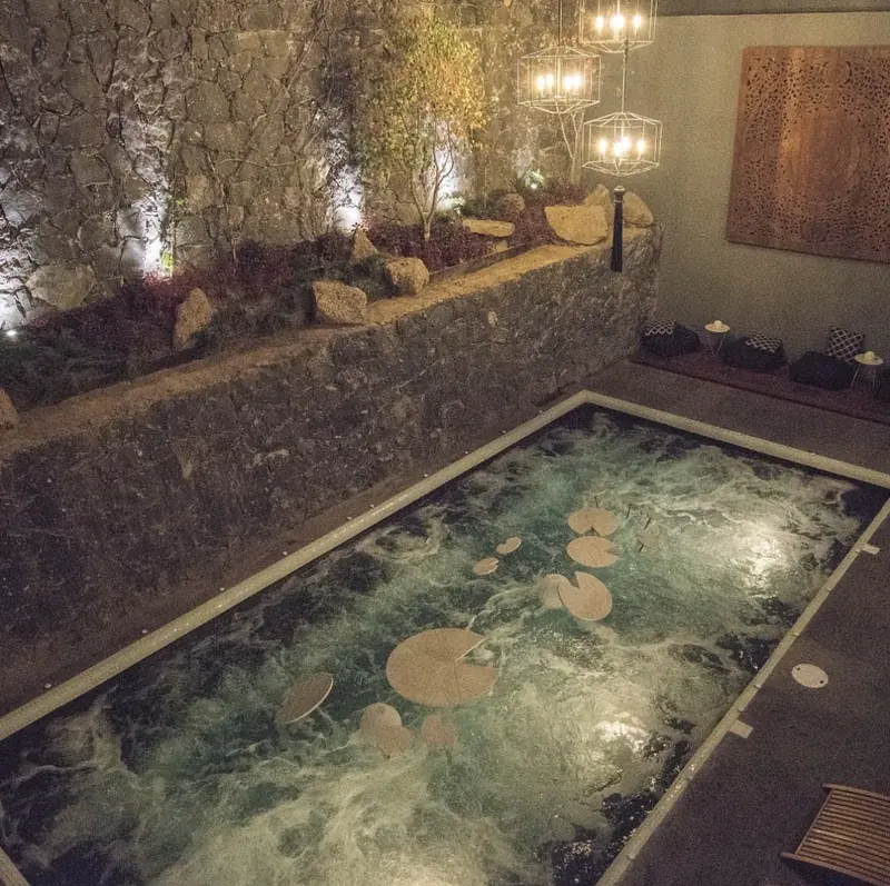 Spa interior con muro de piedra e iluminacion calida